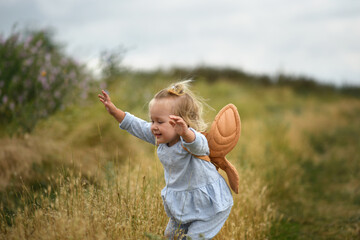Little beautiful girl  with backpack is walking in the field