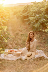 Woman picnic vineyard. Romantic dinner, fruit and wine. Happy woman with a glass of wine at a...