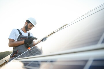 Indian man in uniform working near solar panel.