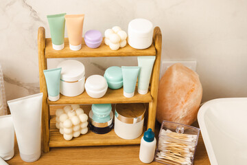 Care cosmetics on the shelf in the bathroom. Cosmetic tube. Cleanser, face and body cream, face roller and gua sha, tonic. Shelf with cosmetics in the interior of the bathroom.Beauty concept. 