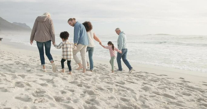 Generations, beach and children walking with holding hands for quality time with interracial people. Love, kids and big family with support at ocean for vacation of bonding or adventure in outdoor.