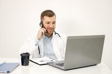 Caucasian doctor sitting at workplace and using laptop
