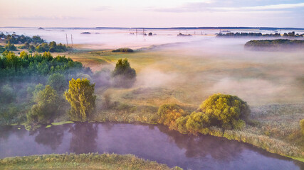 Aerial view of rural landscape with river and lush trees in fog