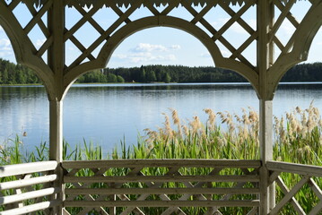 View of the lake, thickets of reeds on the shore, a forest from a wooden gazebo. Bokeh background.