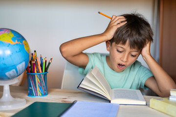 Elementary Age Boy Reading A Book Is Amazed. Concept Of Education And Back To School