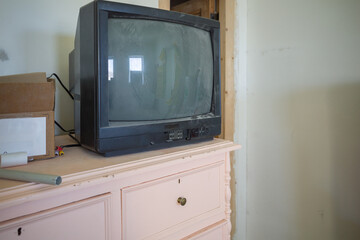 an old tube TV on a pink wooden chest of drawers in an apartment where construction and renovation is underway