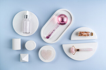 A face massager made of glass and roller, guasha on a white concrete podiums