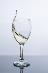 Splash of white wine in a glass on the table