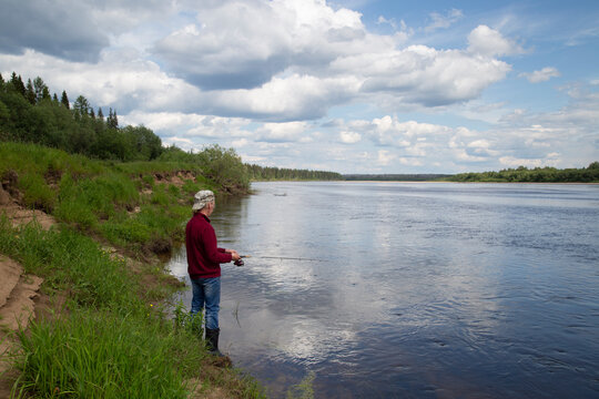 A man is fishing on the river in the summer.Landscape and with clouds on the river.