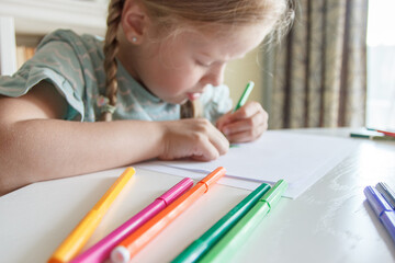 Cute child drawing a picture with colored felt-tip pens. Concept of hobby