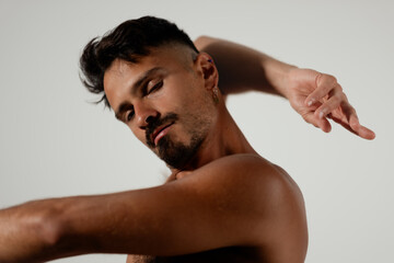 With his eyes closed, a man stretches out his hands and wraps his arms around himself. He looks...