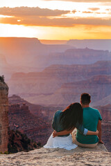 Happy couple on a steep cliff taking in the amazing view over famous Grand Canyon on a beautiful...