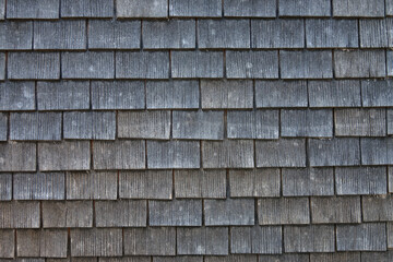 Closeup detail of old wood shingles on the roof of a house in Switzerland is shown.