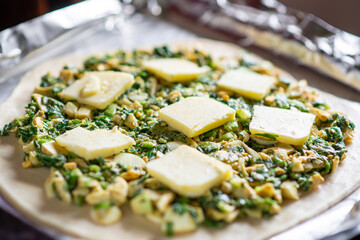 Pie with green onion and egg. Cooking a pie. Pieces of butter are on top.