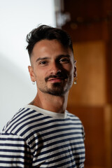 Fototapeta premium Dramatic lighting illuminates a man for a studio portrait. He turns to smile and look at the camera. He has a fresh haircut and a trimmed goatee.
