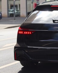 Black sedan sports car closeup. Sleek car background image with LED tail lights bright. 