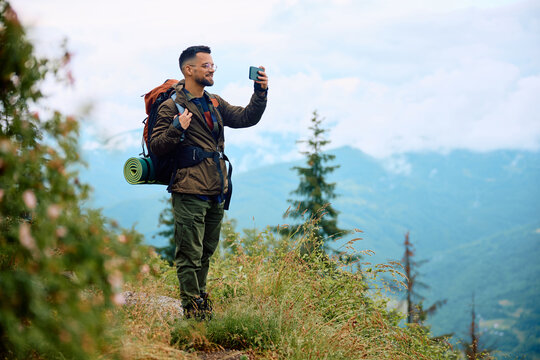 Happy Hiker Using Mobile Phone While Taking Photos Of Nature.