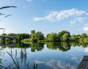 Panorama rzeki Odry w tle most lekko pochmurna pogoda, błękit nieba zieleń przy brzegu, pora letnia, Odra w odcinku województwa Opolskiego	