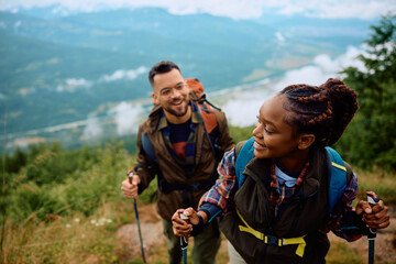 Couple of hikers walking on hill while using hiking poles.