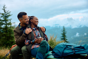 Carefree couple enjoys in view while taking break during hiking in nature. - obrazy, fototapety, plakaty