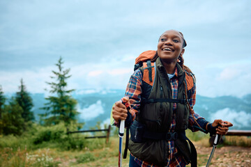 Fototapeta na wymiar Happy African American female hiker walking up hill.