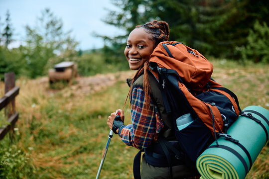 Happy black woman hiking in mountains and looking at camera.
