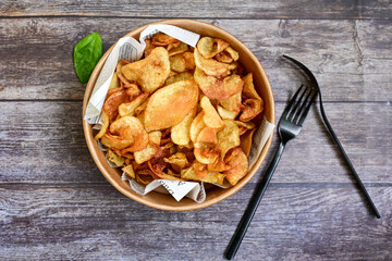 Delicious home made potato chips with sea salt and black pepper against a rustic background. Delicious snack served with sauce. Fast food.Beer snacks