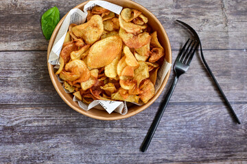Delicious home made potato chips with sea salt and black pepper against a rustic background. Delicious snack served with sauce. Fast food.Beer snacks