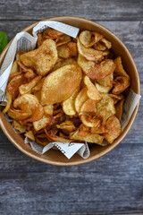 Delicious home made potato chips with sea salt and black pepper against a rustic background. Delicious snack served with sauce. Fast food.Beer snacks