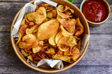 Delicious home made potato chips with sea salt and black pepper against a rustic background. Delicious snack served with sauce. Fast food.Beer snacks