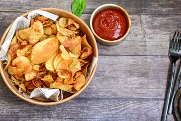 Delicious home made potato chips with sea salt and black pepper against a rustic background. Delicious snack served with sauce. Fast food.Beer snacks