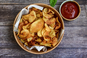 Delicious home made potato chips with sea salt and black pepper against a rustic background. Delicious snack served with sauce. Fast food.Beer snacks