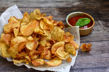 Delicious home made potato chips with sea salt and black pepper against a rustic background. Delicious snack served with sauce. Fast food.Beer snacks