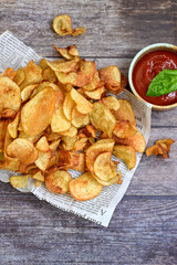 Delicious home made potato chips with sea salt and black pepper against a rustic background. Delicious snack served with sauce. Fast food.Beer snacks
