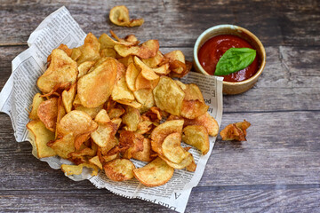 Delicious home made potato chips with sea salt and black pepper against a rustic background. Delicious snack served with sauce. Fast food.Beer snacks