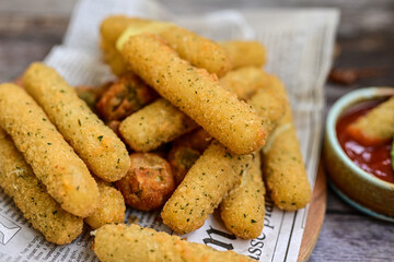 Vegetarian iitalian cheese breaded  oven baked  mozzarella sticks with  fresh basil on wooden background.Italian street food.
