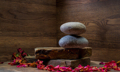 podium with dry rose petals.composition with rose petals and stone on brown wooden background for...