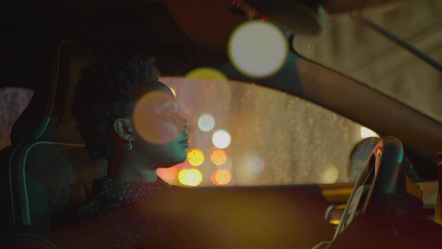 Female Driver Driving Car in the City at Night traffic lights - Blurred Bokeh Background - POV Car Point of View