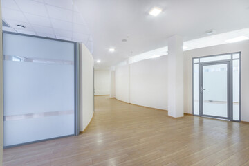 Fototapeta premium A bright corridor with curved lines in a modern office building. Brown laminate, glass .doors.