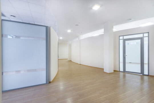 A bright corridor with curved lines in a modern office building. Brown laminate, glass .doors.