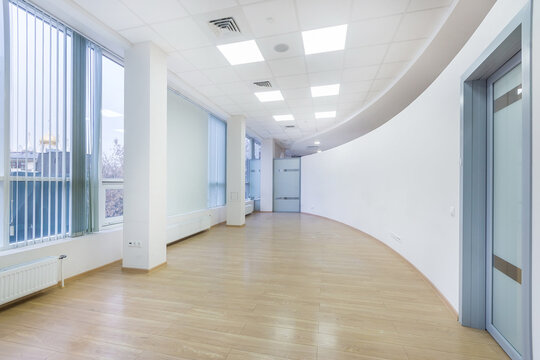 An empty office space with a curved wall shape in a modern building. Panoramic windows with blinds. The room is ready to install furniture and appliances.
