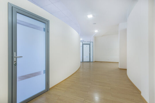 A corridor with beautiful curved lines in a modern office. White wall decor, glass doors.
