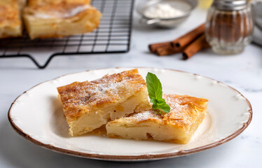 Greek pie called Bougatsa with cheese slightly blurred cross section and selective focus on powdered sugar and cinnamon