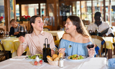 Women lesbian lgbt couple enjoying dinner with wine and having conversation at restaurant