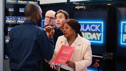 Black Friday shopping madness. Group of mad diverse clients push security guard to enter first into...