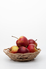Red apples in a wicker plate on a white background