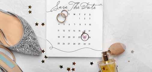 Calendar with marked date, wedding rings and bridal accessories on light background
