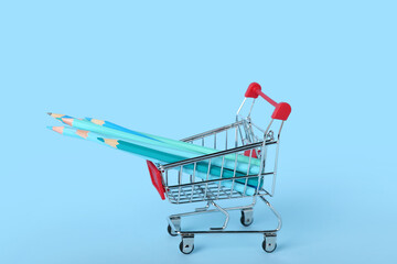 Shopping cart with pencils on blue background