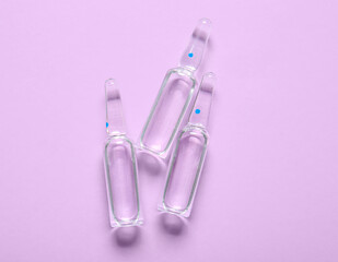 Medical ampules on lilac background