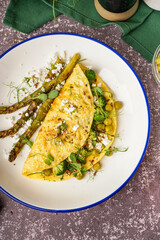 Tasty omelet with broccoli, asparagus and pea on grey background